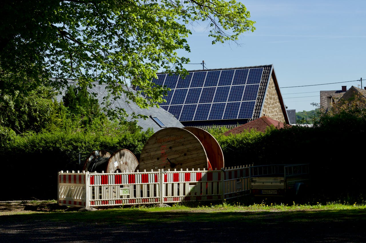 Barn with solar panels and cable reels in rustic countryside setting.